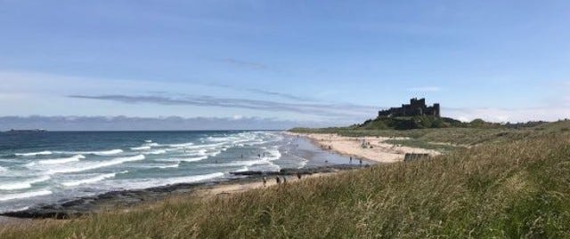 sandy beach with castle on hill in background