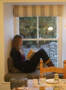 Girl sitting on the window seat reading