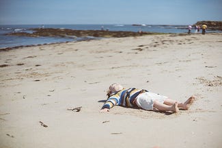 Child laying on the sandy beach